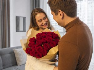 19 роз — мужчина дарит жене пышный букет из 19 роз красных Red Naomi в кремовой упаковке на годовщину в современной квартире