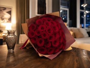 35 роз — большой букет 35 красных Red Naomi на круглом столе в современной квартире на юбилейный вечер