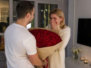 39 роз — мужчина дарит жене пышный букет из 39 роз красных Red Naomi в кремовой упаковке на годовщину в современной квартире