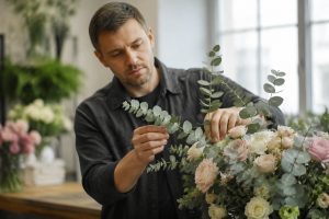 Флорист в студии собирает букет с эвкалиптом parvifolia