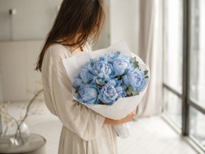 Голубые пионы — букет окрашенных пионов в руках девушки в льняном платье в светлой минималистичной квартире