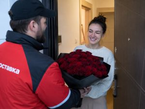 Розы Кения — девушка получает букет 25 шт глубоко-красных от курьера в квартире