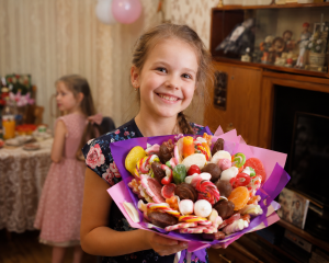Сладкий букет — девочка 8 лет на дне рождения держит букет лолипопов и шоколадных конфет в крафтовой упаковке